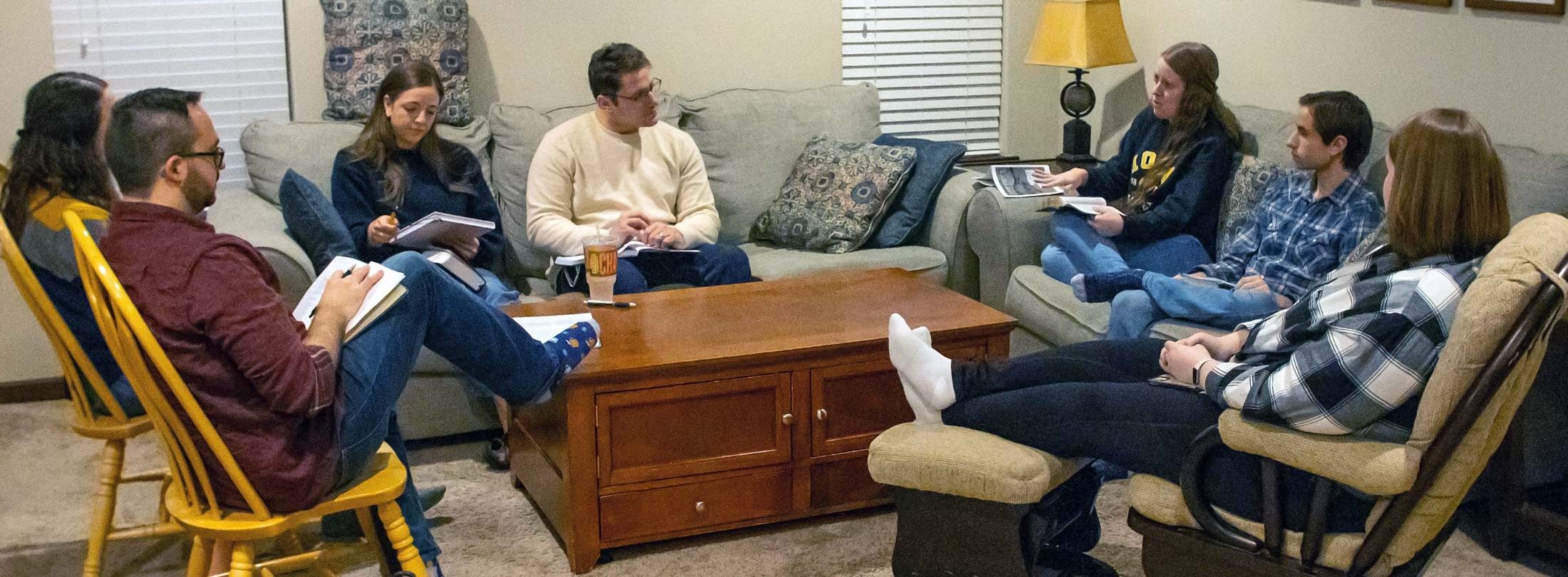 adults sitting on couches and chairs