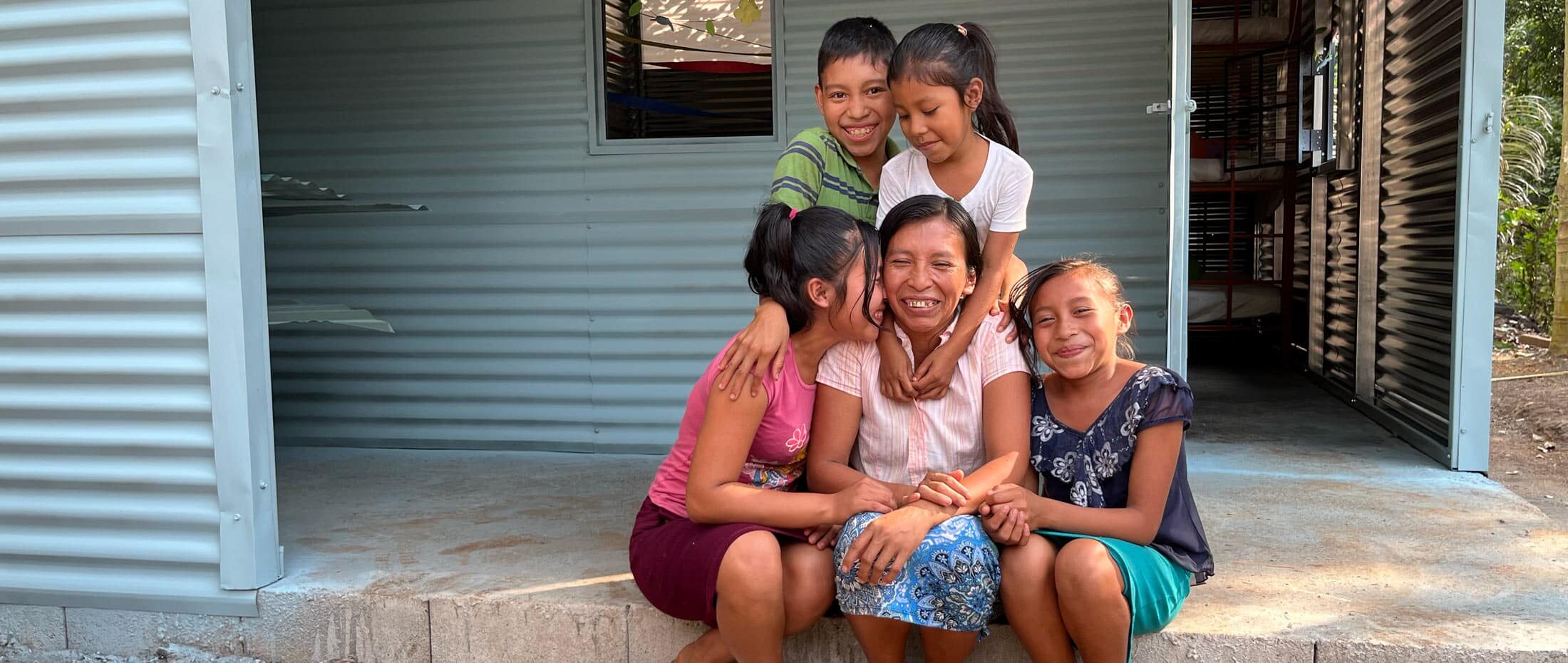 guatemalan family sitting by their new home